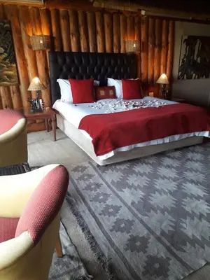a bedroom with a large bed with red pillows at Hartbeespoortdam Lodge in Hartbeespoort