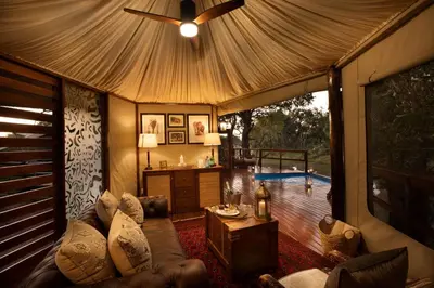 a living room with a couch and a ceiling fan at Hamiltons Tented Camp in Mluwati Concession