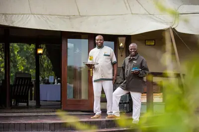 two men are standing outside of a building at Hamiltons Tented Camp in Mluwati Concession