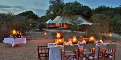 a group of tables and chairs in front of a tent at Hamiltons Tented Camp in Mluwati Concession