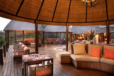 a patio with couches and tables and a large umbrella at Hoyo Hoyo Safari Lodge in Mluwati Concession