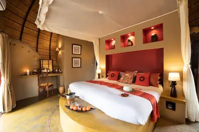 a bedroom with a large bed with red pillows at Hoyo Hoyo Safari Lodge in Mluwati Concession