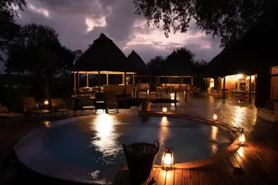 a swimming pool at night with lights around it at Hoyo Hoyo Safari Lodge in Mluwati Concession
