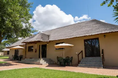 a house with chairs and umbrellas in front of it at Fumani Game Lodge in Modimolle