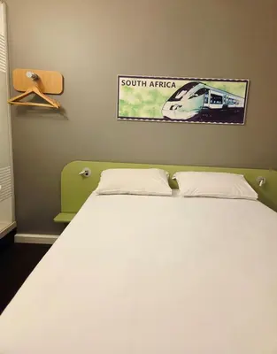 a bed in a room with a sign on the wall at SUN1 MIDRAND in Midrand