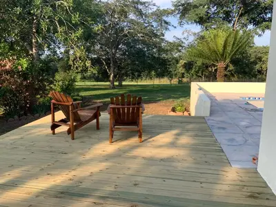 two chairs and a table on a wooden deck at Bergdale Cottages in Hazyview