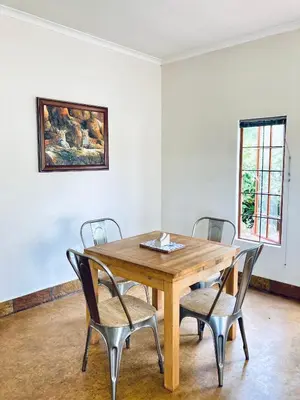 a dining room with a wooden table and chairs at Bergdale Cottages in Hazyview
