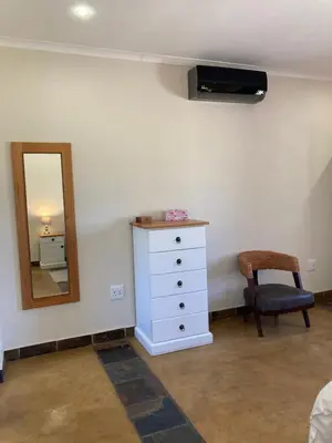 a bedroom with a dresser and a mirror and a chair at Bergdale Cottages in Hazyview