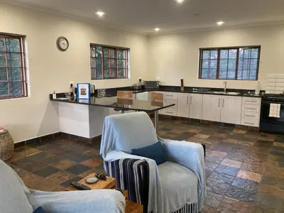 a large kitchen with two chairs and a table at Bergdale Cottages in Hazyview