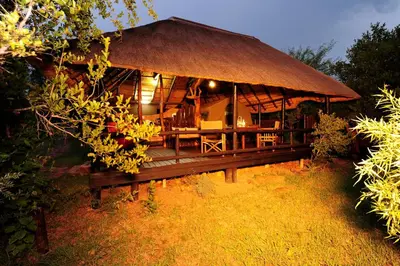 a large hut with a deck in the grass at iKhaya LamaDube Game Lodge in Klipdrift