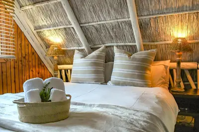 a bedroom with a bed with pillows and two lamps at iKhaya LamaDube Game Lodge in Klipdrift