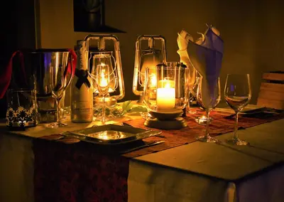 a table with glasses and candles and a bottle of wine at iKhaya LamaDube Game Lodge in Klipdrift