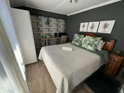 a bedroom with a large bed and a table at Paul & Mollie's Guest House in Brits