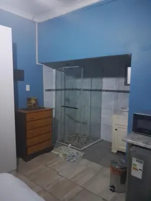 a bathroom with a shower and a dresser in a room at Paul & Mollie's Guest House in Brits
