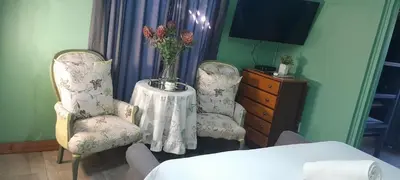 a room with two chairs and a table with a vase of flowers at Paul & Mollie's Guest House in Brits