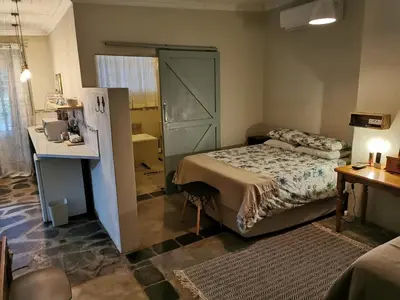 a small bedroom with a bed and a desk and a table at MacNut Bed and Breakfast in Nelspruit