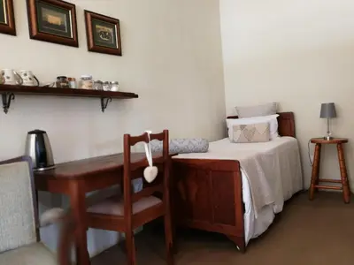 a bedroom with a bed and a desk and a table at MacNut Bed and Breakfast in Nelspruit
