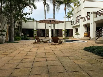 a patio with chairs and an umbrella next to a building at Telestai Guest House in White River