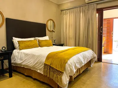 a bedroom with a large bed with a yellow blanket at Telestai Guest House in White River