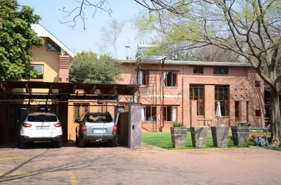 two cars parked in front of a brick house at Bed & Breakfast in Hatfield in Pretoria