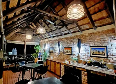 a restaurant with tables and chairs and a brick wall at Crocodile Kruger Safari Lodge in Marloth Park