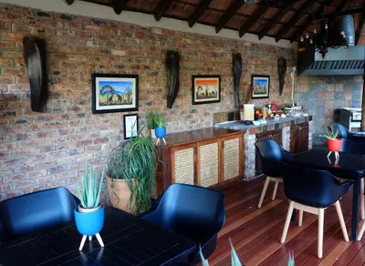 a bar with blue chairs and a brick wall at Crocodile Kruger Safari Lodge in Marloth Park