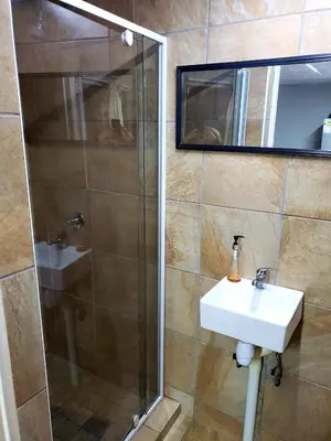 a bathroom with a sink and a shower with a mirror at 13 @ Rhinoroad Nelspruit in Nelspruit