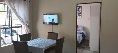 a room with a table and a television on the wall at 13 @ Rhinoroad Nelspruit in Nelspruit