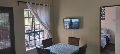 a dining room with a table and a television on the wall at 13 @ Rhinoroad Nelspruit in Nelspruit