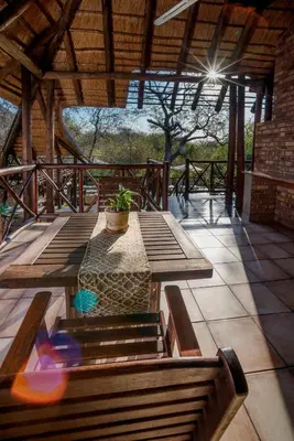 a patio with benches and a table with a potted plant at La Kruger Lifestyle Lodge - No Loadshedding in Marloth Park