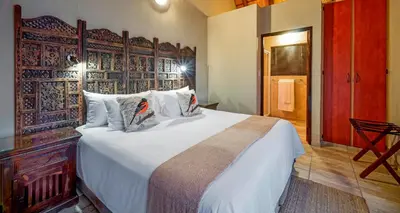 a bedroom with a large bed with a wooden headboard at La Kruger Lifestyle Lodge - No Loadshedding in Marloth Park