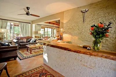 a living room with a counter with a vase of flowers at La Kruger Lifestyle Lodge - No Loadshedding in Marloth Park