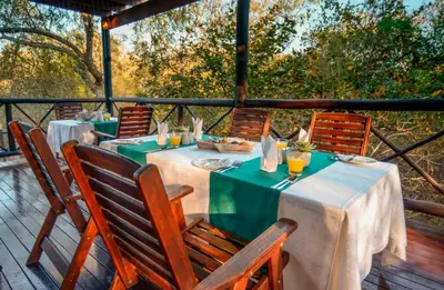 a table with green and white tables and chairs on a deck at La Kruger Lifestyle Lodge - No Loadshedding in Marloth Park