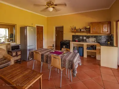 a kitchen with a table with chairs and a refrigerator at KwaThabisile Bush Retreat in Cullinan