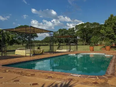 a swimming pool with a pavilion next to a field at KwaThabisile Bush Retreat in Cullinan