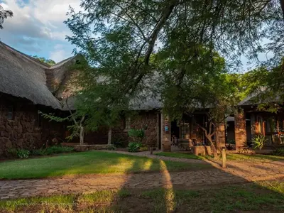 a stone house with a thatched roof at KwaThabisile Bush Retreat in Cullinan