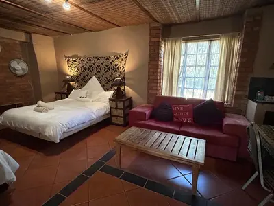 a bedroom with a bed and a red couch at KwaThabisile Bush Retreat in Cullinan