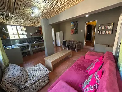 a living room with a pink couch and a kitchen at KwaThabisile Bush Retreat in Cullinan