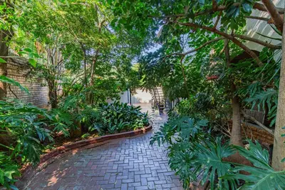 a walkway through a garden with trees and plants at Pumleni Guesthouse in Hartbeespoort