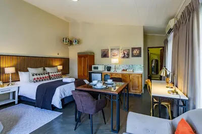 a hotel room with a bed and a table at Pumleni Guesthouse in Hartbeespoort