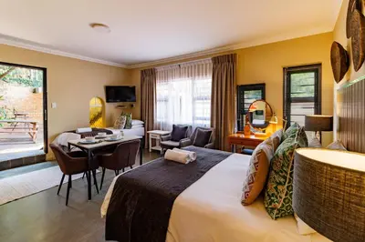 a hotel room with a bed and a living room at Pumleni Guesthouse in Hartbeespoort