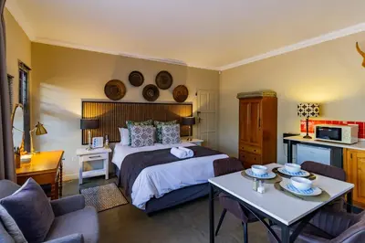 a bedroom with a bed and a table in a room at Pumleni Guesthouse in Hartbeespoort