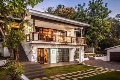 a large white house with a balcony and stairs at The Aloes in Nelspruit