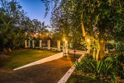 a walkway in a park with a tree and a fence at The Aloes in Nelspruit