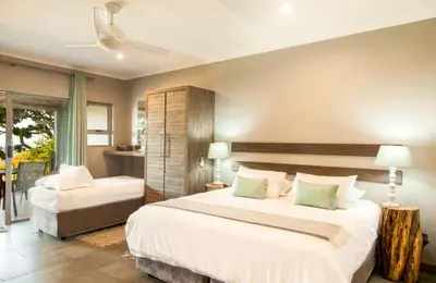a bedroom with a large white bed and a window at @Nature Luxury Cottages in Nelspruit