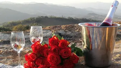 a bouquet of red roses next to two glasses of wine at @Nature Luxury Cottages in Nelspruit