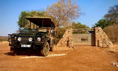 a green jeep parked next to a building with an elephant at Sangasava Safari Lodge in Balule Game Reserve