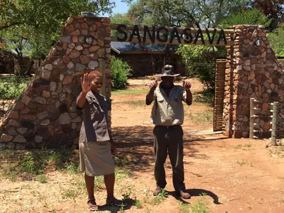 a man and a boy standing in front of a gate at Sangasava Safari Lodge in Balule Game Reserve