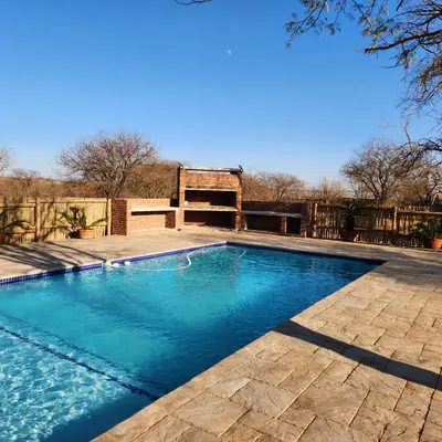 a swimming pool with blue water in a yard at Grincourt B&B- with No Load shedding in Polokwane