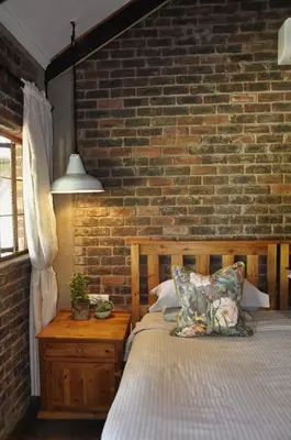 a bedroom with a bed and a brick wall at Grincourt B&B- with No Load shedding in Polokwane